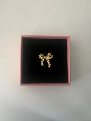 Guldfärgad rosett ring  - Säljer en söt Stockholmstil ring med en guldig rosett på. Ringen är justerbar! Jag säljer flera snygga, liknande ringar, blir billigare vid köp av flera!❤️