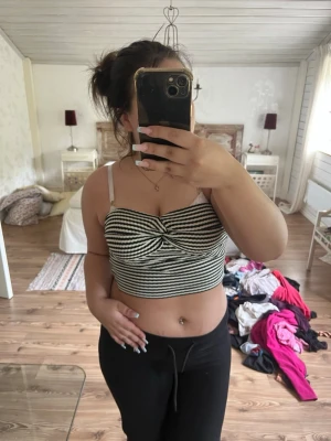 Randig croppad linnetopp - Säljer en croppad linnetopp med svartvita ränder och twistad detalj framtill. Toppen har smala axelband och en figurnära passform som passar perfekt till både jeans och kjol. Superenkel att styla för en trendig look.