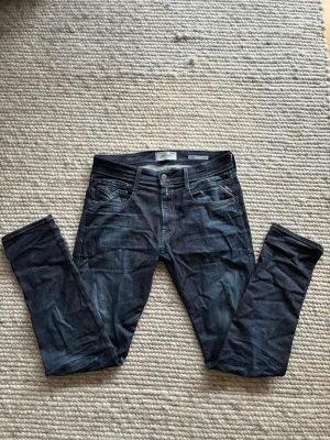 Replay anbass 32/32 - Snygga mörkblå jeans från Replay med klassisk femficksdesign och detaljerade sömmar. Jeansen har en smal passform och är tillverkade i stretchigt denimtyg för extra komfort. Perfekta för en trendig och avslappnad look.