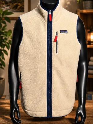 Beige fleeceväst från Patagonia - Säljer en beige fleeceväst från Patagonia med marinblå detaljer och röda dragkedjor. Västen har hög krage, tre fickor med dragkedja och är tillverkad i mjukt teddyfleece-material. Perfekt för lager-på-lager och outdoor-vibe.