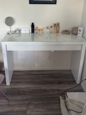 Sminkbord med Glaskiva  - Hej!  Jag säljer mitt sminkbord då jag inte använder det längre. Det är ett jättebra och fint sminkbord men har tyvärr bara använts som avlastningsbord det senaste och tar bara upp onödig plats hos oss. Bordet är från IKEA och är gjort av trä samt har en glaskiva på toppen vilket är en väldigt fin detalj. Den har några små defekter som syns på bilderna men annars så är den i bra skick. Utgångspriset är 1 000kr men är öppen för förhandling vid snabb affär   OBS! Bor på bottenvåning men du som köp