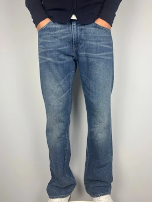 Bootcut Levis 527 Vintage Jeans - Levi’s 527 vintage bootcut jeans Snygga fades framtill som ger jeansen extra karaktär och en snygg bootcut passform.  Färg: Blå med snygga fades framtill Passform: Bootcut  Storlek: W34 L32 Skick: A-B Grade Mått (±1 cm): A: 43 cm B: 107 cm C: 23 cm D: 30 cm Passar bra på modellen på bilden som är 189 cm lång och väger 82 kg.  Tveka inte att höra av dig vid frågor eller funderingar.  Skickas snabbt!