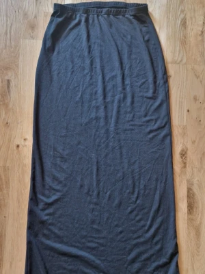 Långkjol - En enkel och stilren svart långkjol med resår i midjan. Kjolen är rak men figurnära i modellen och gjord i mjukt bomullstyg, perfekt för en avslappnad och clean look. 