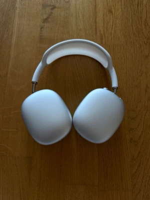 Apple AirPods Max vita hörlurar - Snygga vita over-ear hörlurar från Apple, modell AirPods Max. De har en stilren design med mjuka öronkuddar i mesh och båge i aluminium och textil. Perfekta för dig som vill ha grymt ljud och modern look.
