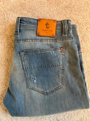 Ljusblå jeans från Tramarossa - Säljer ett par ljusblå jeans från Tramarossa som är i helt nytt skick. Jeansen har en snygg läderpatch med logga bak i midjan och raka ben. Tillverkade i mjukt denimtyg som ger en avslappnad look.