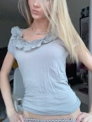 Ljusgrå topp med volangdetalj - Supersöt ljusgrå topp med volang runt ringningen. Från Hm💕💕