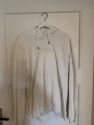 Vit hoodie från Peak Performance - Snygg vit hoodie från Peak Performance med broderad logga på bröstet, 3 fläckar dom 2 övre går nog bort i tvätten den nedre pricken går tyvärr inte bort 