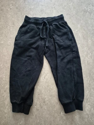 Mjukisbyxor - Mysiga svarta mjukisbyxor med resår i midjan och dragsko för perfekt passform. Byxorna har ribbade muddar vid bensluten och två sidofickor. Tillverkade i mjukt och bekvämt material, perfekta för chill dagar.