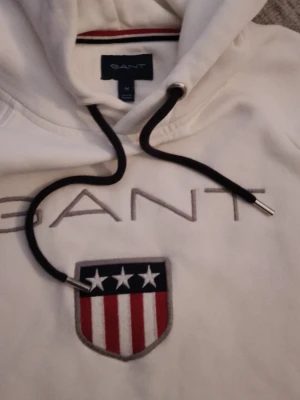 Vit hoodie från GANT med brodyr - Snygg vit Hoodie från GANT. Ord pris 1199kr hoodien är knappt använd. Skriv gärna för frågor.