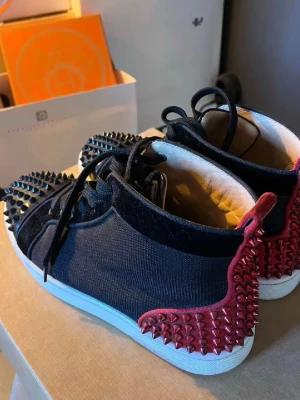 Christian Louboutin skor - Säljer dessa supersnygga, coola, unika sneakers från Christian Louboutin med röda och svarta nitar😍Säljer då de tyvärr är för stora för mig vanligtvis har storlek 39-40! Du får med box och allt som tillhör! Dessa säljs inte längre men nypriset ligger troligen runt 12-15 tusen kr❣️Perfekt nu till våren och sommaren! Passar både tjej och kille 