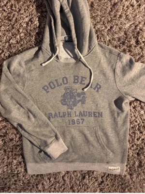 Grå raffe hoodie🙌🤩 - Grå hoodie från Ralph Lauren med Polo Bear-tryck och texten '1967' på bröstet. Hoodien är i storlek S och riktigt najs🤩🙌