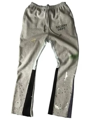 Grå mjukisbyxor Gallery Dept. - Grå mjukisbyxor från Gallery Dept. med svart och vit färgdetalj på benen, färgstänk och tryckt logga på vänster sida. Byxorna har resår i midjan med dragsko och raka ben. Perfekt för en avslappnad och trendig look. Lappar sitter på.
