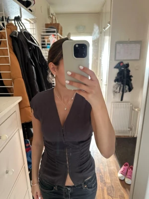 Mörkgrå v-ringad topp från Weekday - Snygg mörkgrå topp från Weekday med v-ringning och croppad passform. Toppen har korta ärmar och knäppning framtill med små krokar. Tillverkad i ett mjukt linnematerial🤗