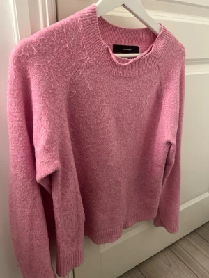 Rosa stickad tröja från Vero Moda - Mysig rosa stickad tröja från Vero Moda. Tröjan har en avslappnad passform och är perfekt för kyliga dagar. Materialet är väldigt mjukt och fluffigt. 