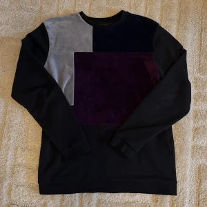 La Vichy sweatshirt  - Blockfärgad sweatshirt från Le Vichy med coola paneler i mörkblått, grått och vinrött. Tröjan har långärmade svarta ärmar och mjukt sammetstyg på framsidan. Rund halsringning och relaxed passform, perfekt för dig som gillar stilrena detaljer. Inga skador 