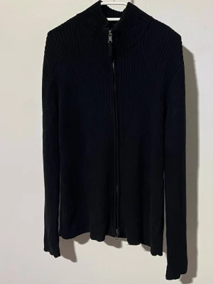 Svart ribbstickad ziptröja Lauren Ralph Lauren - Säljer en svart ribbstickad tröja med dragkedja framtill och hög krage. Tröjan har lång ärm och är tillverkad i ett mjukt, stretchigt material. Enkel och stilren design som passar till det mesta.