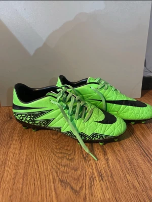 Nike Hypervenom gröna fotbollsskor - Säljer ett par grymma Nike Hypervenom fotbollsskor i neon-grönt med svarta detaljer och mönster. Skorna är knappt använda som dem är hyfsat ny skick bara lite smutsiga då jag har använt dem 3 gånger annars inga konstigheter 