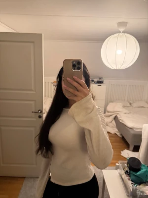 Vit ribbad långärmad topp - Säljer en vit ribbad långärmad topp med figurnära passform. Toppen har en lätt struktur i materialet. Däremot har tröjan en liten fläck men inget man tänker på när man har på sig den.