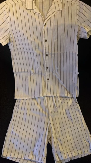 Vita randiga shorts i bomull - Säljer ett set. Shorts och T-shirt perfekt för sommaren. Passformen är normal och stilen är enkel men clean.