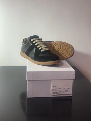 Maison Margiela Gats - Säljer ett par Maison Margiela Gats i svart (storlek 43) som kommer med box. Endast använda 4–5 gånger, mycket fint skick utan skador. Perfekta för en stilren och clean outfit. 