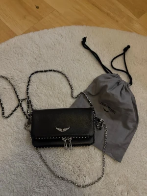 Svart handväska Zadig & Voltaire - Snygg svart handväska från Zadig & Voltaire i läder med silverfärgade kedjedetaljer och emblem framtill. 