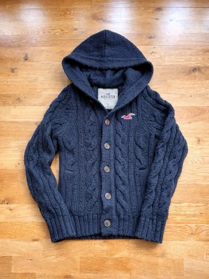 Stickad Vintage Hollister cardigan/hoodie (y2k) - Säljer nu denna otroligt snygga vintage Hollister cardigan i färgen marinblå. Tröjan är i skick 8/10. Hoodien är i storlek L men sitter som M/L. Tröjan består av 40 % ull. Skriv om ni har mer funderingar 😊 