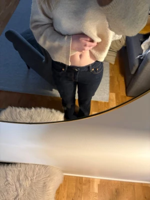 Mörkblå jeans - Säljer ett par mörkblå jeans. Klassisk femficksmodell med gylf och knapp framtill. Jeansen har kontrastsömmar och är tillverkade i ett stadigt denimtyg som ger en snygg siluett. De är avklippta i längden men inget man tänker på. 