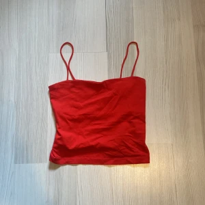 Röd linne från Gina Tricot - Säljer ett snyggt rött linne från Gina Tricot. Det har smala axelband och är perfekt för sommardagar. Materialet är mjukt och bekvämt, vilket gör det till ett måste i garderoben. Passar både till vardags och fest!