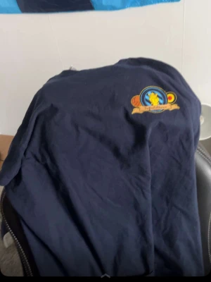 Sofialäktaren tröja - Mörkblå t-shirt med tryck fram och bak från Sofialäktaren Stockholm. Framsidan har ett färgglatt emblem med text och baksidan har stor ljusblå text. Klassisk passform och rund hals, perfekt för dig som vill visa ditt stöd för laget.