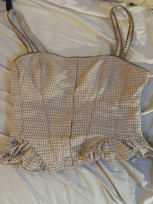 Beige rutig topp med volang - Säljer en söt beige topp från Zara, rutig och EXTREMT snygg!!! Perfekt fest topp för både sommar och höst🥰 ÄLSKAAR