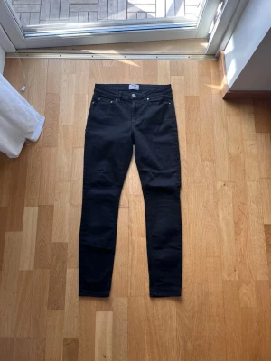 Svarta skinny jeans från Acne studios  - Säljer ett par svarta skinny jeans från Acne studios  med klassisk femficksdesign och hög midja. Jeansen har smal passform och är tillverkade i stretchigt material för extra komfort. Perfekta till en avslappnad eller trendig look.
