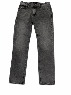 Jack & Jones grå straight leg jeans – storlek W30 L32 - Märke: Jack & Jones Storlek: W30 L32 Skick: Mycket bra Defekter: Inga  Dessa grå straight leg-jeans är ett mångsidigt val för vardagsbruk. Den klassiska designen har en mid-rise passform som sitter bekvämt i midjan, vilket gör dem perfekta för daglig styling. Matcha dem med en enkel t-shirt för en avslappnad look eller klä upp dem med en skjorta för en kväll ute. Den subtila tvätten ger lite extra karaktär och gör dem till ett stilrent tillskott i garderoben. 