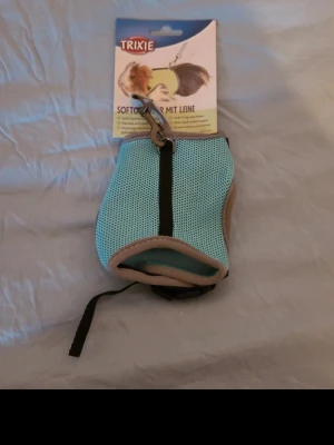 Blå sele för smådjur från Trixie - Praktisk blå sele för smådjur som marsvin eller kanin från Trixie. Selen är tillverkad i ett mjukt meshmaterial med grå kant och svart dragkedja. Perfekt för promenader med ditt husdjur och enkel att justera.