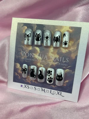 Meowish (XS);Short Square;Curved - Unika handgjorda press-on naglar i pärlemor med svarta kattmotiv, tassavtryck, rosetter och söta detaljer. Naglarna har en glittrig finish och motiv som kattansikten, tassar och rosetter. Perfekt för dig som älskar djur och vill ha något extra på naglarna.XS: 14 mm, 11 mm, 11,5 mm, 10 mm, 8 mm 