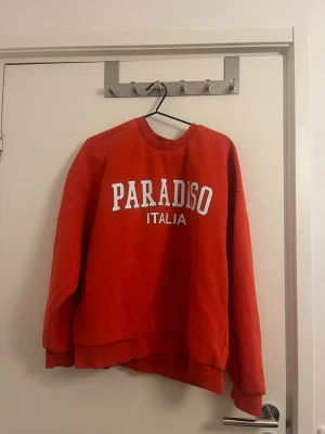 Orange hoodie med tryck - Cool orange sweatshirt från Gina Tricot med texten 'PARADISO ITALIA' i vitt framtill. Tröjan är knappt använd och i mycket bra skick. Storlek XL men skulle nog passa även en L 🧡