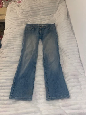 Blå bootcut jeans från KappAhl - Ett par klassiska blå bootcut jeans från KappAhl, modell BASIC. Jeansen har fem fickor, normal midja och är tillverkade i 98% bomull och 2% elastan för en bekväm stretch. Perfekta för en avslappnad och trendig look.