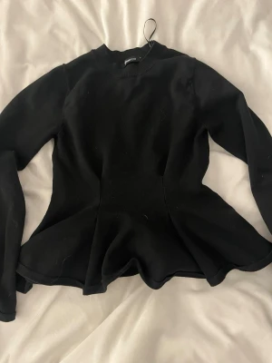 Svart peplumstickad tröja Gina Tricot - Säljer en svart stickad tröja från Gina Tricot i storlek S. Tröjan har lång ärm, rund halsringning och en snygg peplumformad midja som ger en cool siluett. Perfekt till jeans eller kjol för en trendig look.