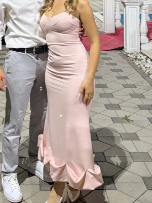 Volang BALKLÄNNING /bröllopsklänning - Elegant ljusrosa långklänning med smala axelband och figurnära passform. Klänningen har en söt volangdetalj längst ner och en mjuk, slät yta som ger ett stilrent intryck. Perfekt för speciella tillfällen och student. Passar även Strl S och M