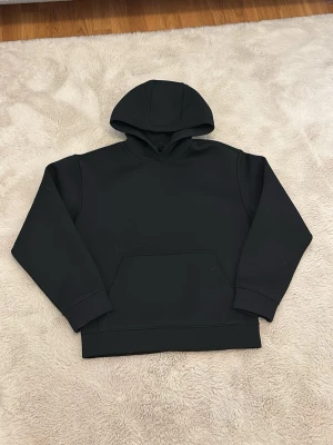 Svart hoodie  - En stilren svart hoodie från H&M med klassisk huva och stor magficka. Tillverkad i mjukt bomullsmaterial som känns skönt mot huden. Perfekt för dig som gillar en enkel och clean look. Passar till det mesta och är lätt att matcha med andra plagg. Köptes för 549 kr och är endast använd 3-4 gånger 