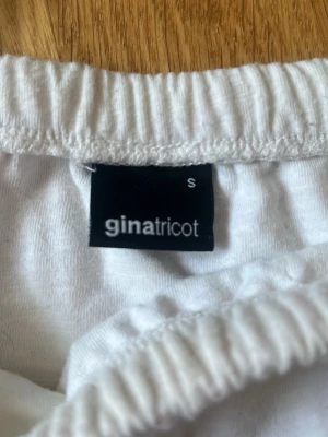 Vit volangkjol från Gina Tricot - Supersöt vit kortkjol från Gina Tricot med flera lager volanger och resår i midjan. Kjolen är gjord i ett mjukt bomullstyg som känns skönt mot huden. Perfekt för dig som vill ha en luftig och trendig kjol till sommaren.