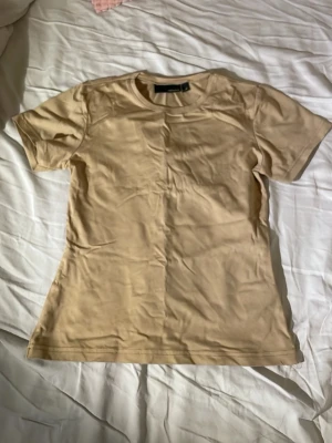 Beige/guldig basic t-shirt från Bik Bok - En enkel och stilren beige t-shirt från Bik Bok. Den är beige med en guldig nyans av nåt slag. Jättesnygg men har tyvärr aldrig kommit till användning💕