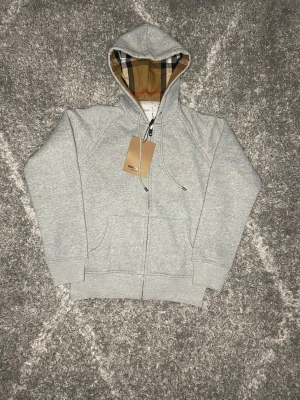 Burberry hoodie grå - Jag säljer en väldigt fin burberry hoodie som är i nyskick, hoodien är i storlek M och passar som en M, skriv gärna till mig vid minsta intresse, perfekt nu till våren🌸🌤️