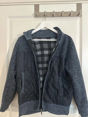 Grå stickad cardigan med quiltade detaljer - Mysig gråmelerad cardiganjacka med stickade ärmar och rygg samt quiltade partier framtill. Jackan har dragkedja, två fickor och en mjuk, rutmönstrad fleece på insidan. Perfekt för lager på lager och chill stil.