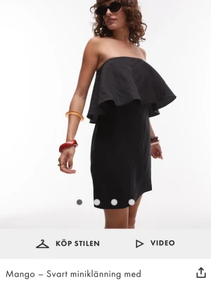 Svart axelbandslös klänning Mango - Trendig svart axelbandslös kortklänning från Mango i storlek M med volang upptill. Klänningen har en rak passform och är perfekt för dig som gillar en stilren look. Köpt för 660kr, klänningen har endast användas en gång. Den har inga defekter.