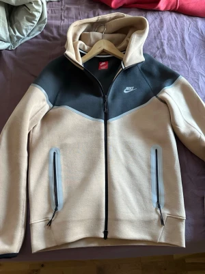 Nike tech fleece beige och svart hoodie med dragkedje - En Nike tech fleece huvtröja med reflex vid blixt 