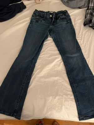 Mörkblå bootcut jeans  - Snygga mörkblå bootcut jeans med klassisk femficksdesign och dragkedja. Jeansen har en lätt tvättad look och är tillverkade i denim med stretch för extra komfort. Perfekta för en avslappnad och trendig stil. Jag är själv då 164 med hyfsat stora vaden och lår men sitter inte tajt