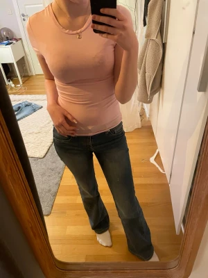 Ljusrosa tight t-shirt - Säljer en ljusrosa t-shirt med rund hals och korta ärmar. Toppen är tight och har en enkel, clean design utan mönster eller detaljer. Perfekt för dig som gillar basic och stilrent. Materialet känns mjukt och stretchigt, troligen bomull eller syntet.