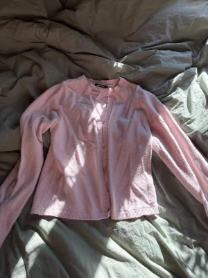 Ljusrosa kofta - Söt ljusrosa kofta med rund halsringning och långa ärmar. Koftan har ribbade muddar vid ärmslut. Koftan är ifrån Gina tricot.