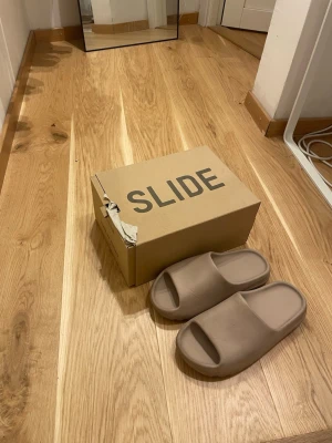 Yeezy Slide  - Säljer ett par Yeezy Slide tofflor i storlek 44. Kartongen får man med