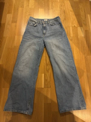 Vida ljusblå jeans från 157 - Säljer ett par klassiska ljusblå jeans från 157 med rak och vid passform. Jeansen har fem fickor, gylf med dragkedja och knapp samt Lee-logga på bakfickan. Perfekta för en avslappnad och trendig look.